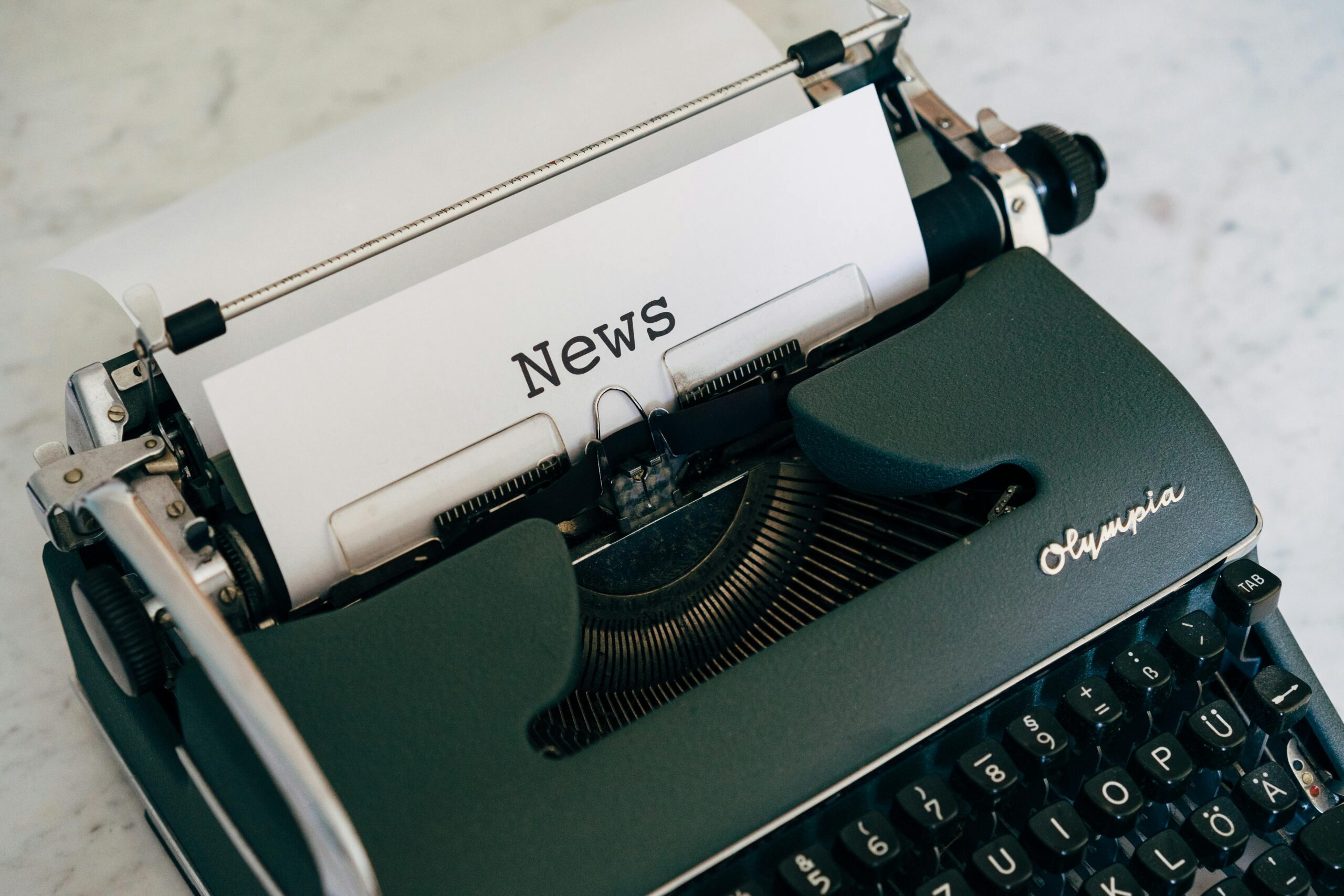 Close-up of an antique typewriter with 'News' on paper.